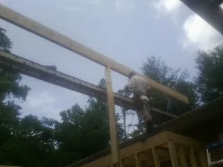 Carpenter setting a ridge beam over a new addition frame — Ice Dam Removal by Roofing Brothers in Long Creek