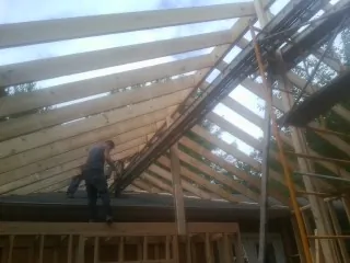 Rafters going up over a new addition with a worker on the wall in Long Creek