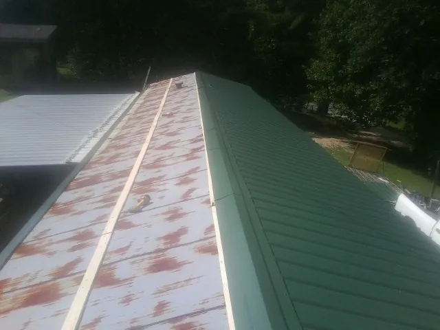 Old rusted panels beside newly installed green metal roofing — Wind Damage Roof Repair by Roofing Brothers in Long Creek