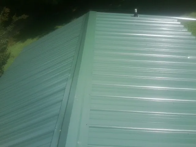 New green metal panels meeting at the ridge of a roof — Flat Roof Repair work by our crew in Long Creek