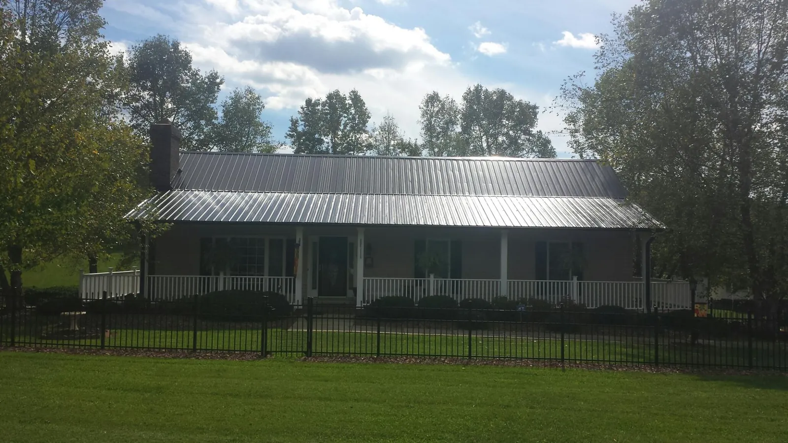 Gray metal roof on a brick ranch with a full width front porch — Gutter Guard Installation work by our crew in Long Creek