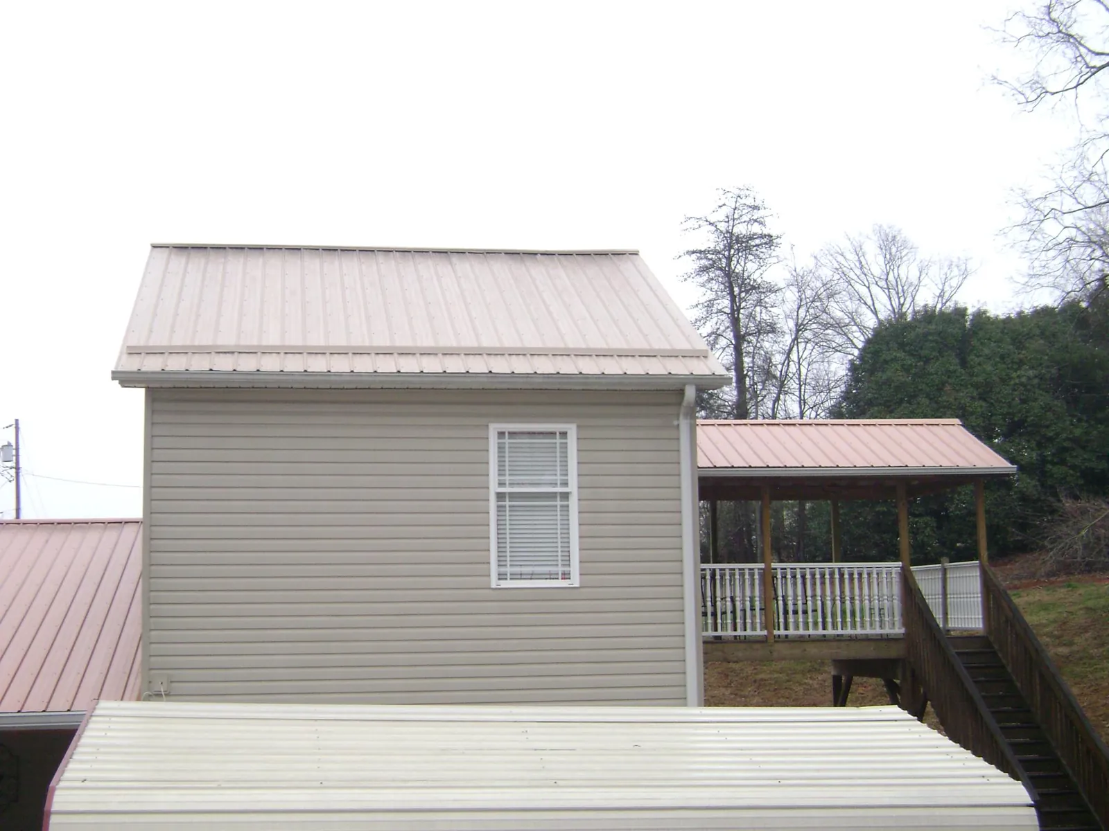 Tan metal roofs on a two story addition and attached porch, from a Roof Replacement job in Long Creek