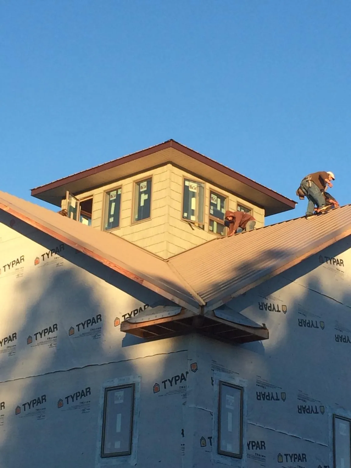 Roofers working around a rooftop cupola on a new metal roof at sunset — Roof Waterproofing in Long Creek by Roofing Brothers
